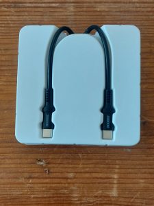 Two black USB-cable ends, pointing downwards in a tightly fitting white plastic case.